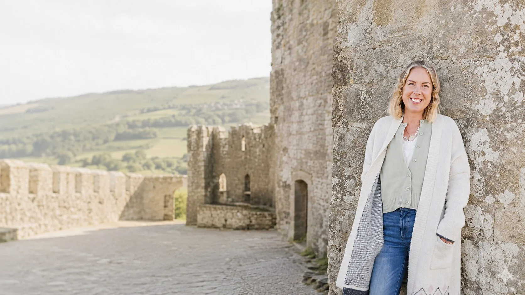 Georgie Durcan standing against a castle wall, the Wicklow hills behind her