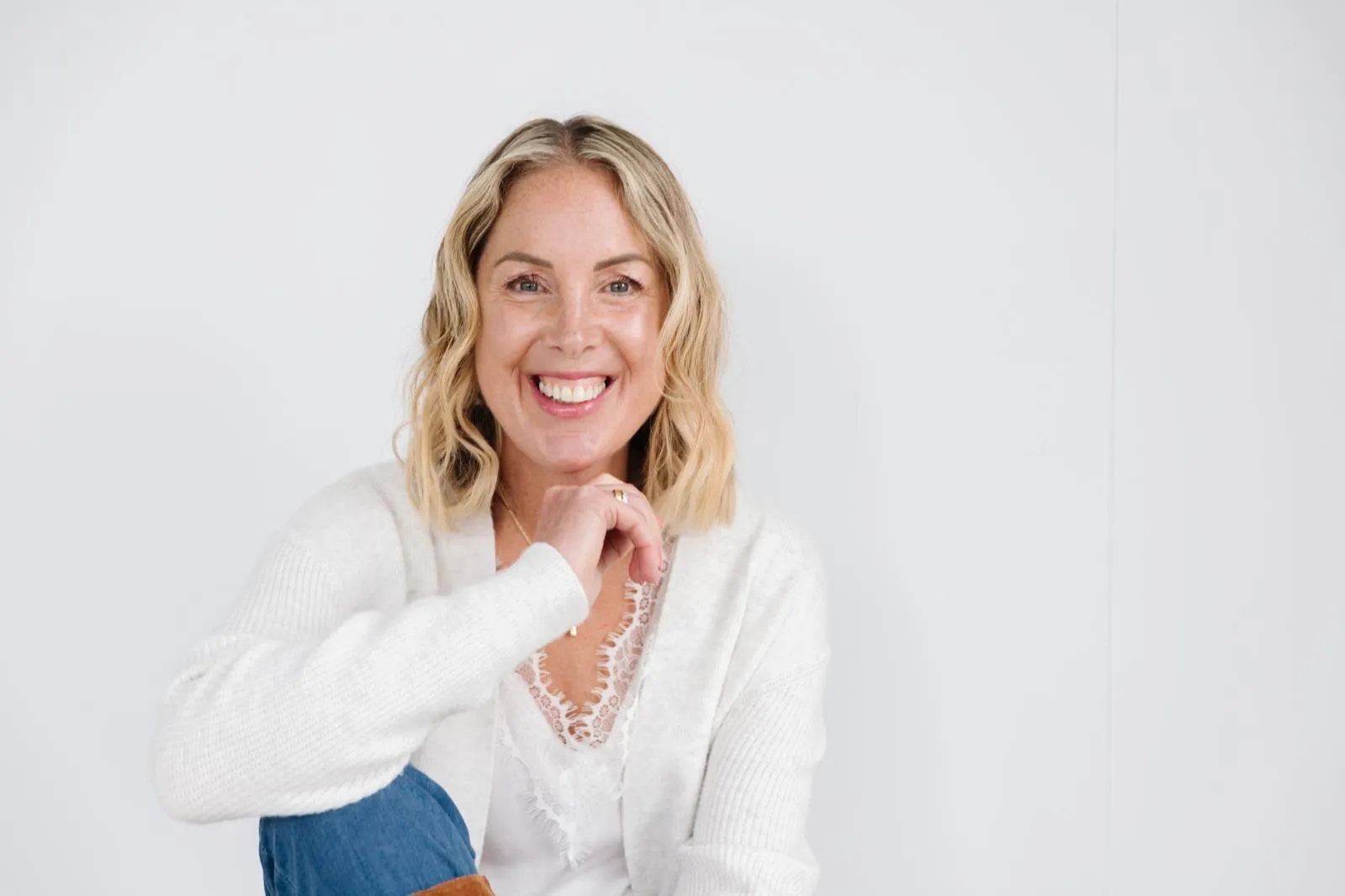 Georgie Durcan smiling, leaning on one hand against a white wall