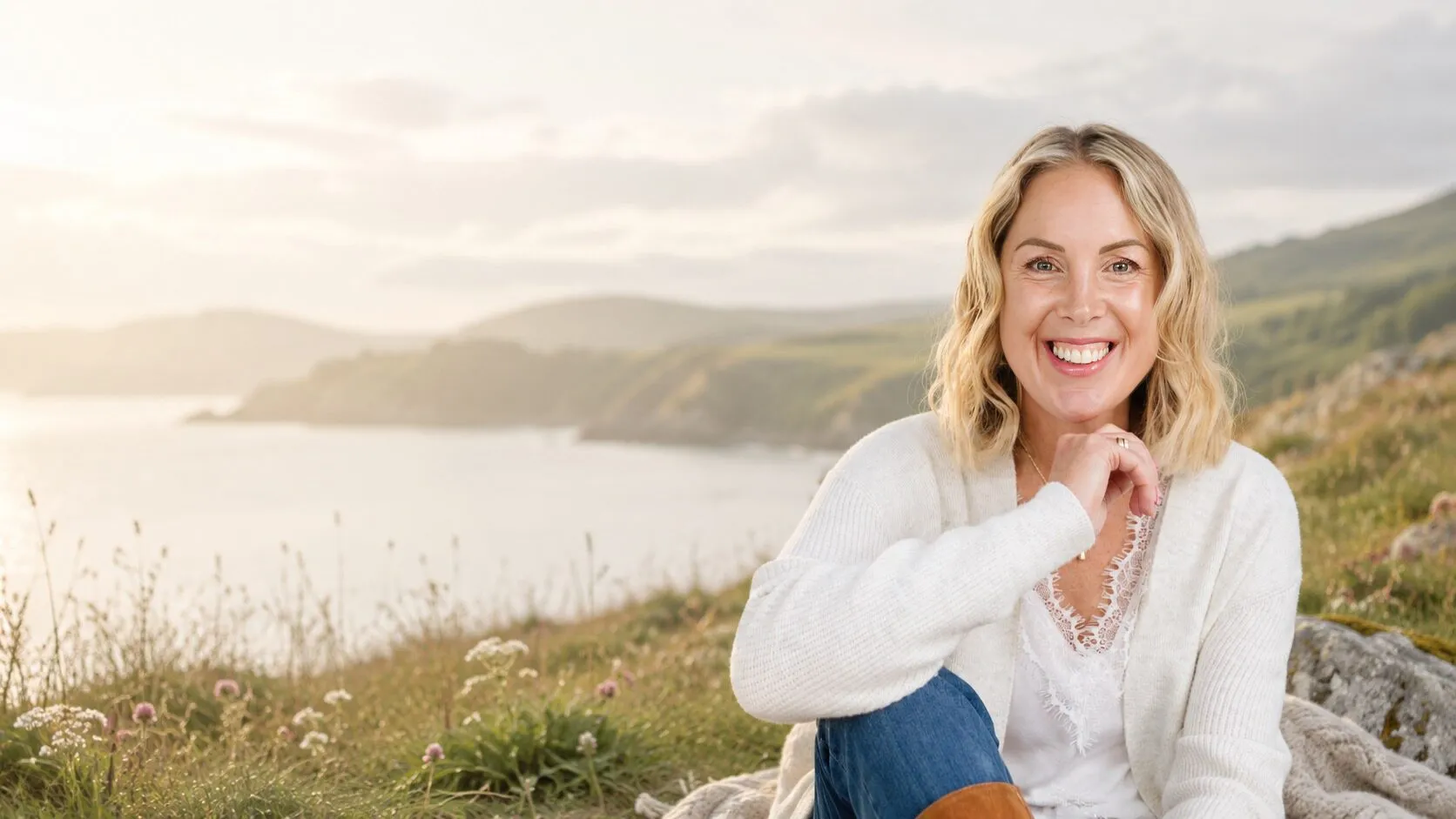Georgie Durcan sitting in the grass on a headland above the sea, Wicklow coast